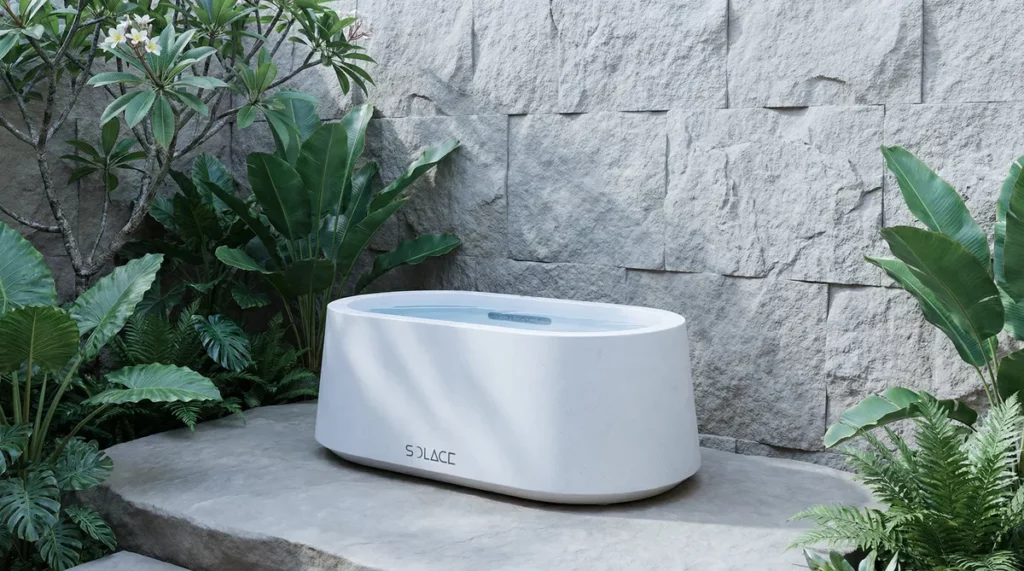 Solace ice bath unit on stone platform surrounded by tropical foliage and stone wall backdrop