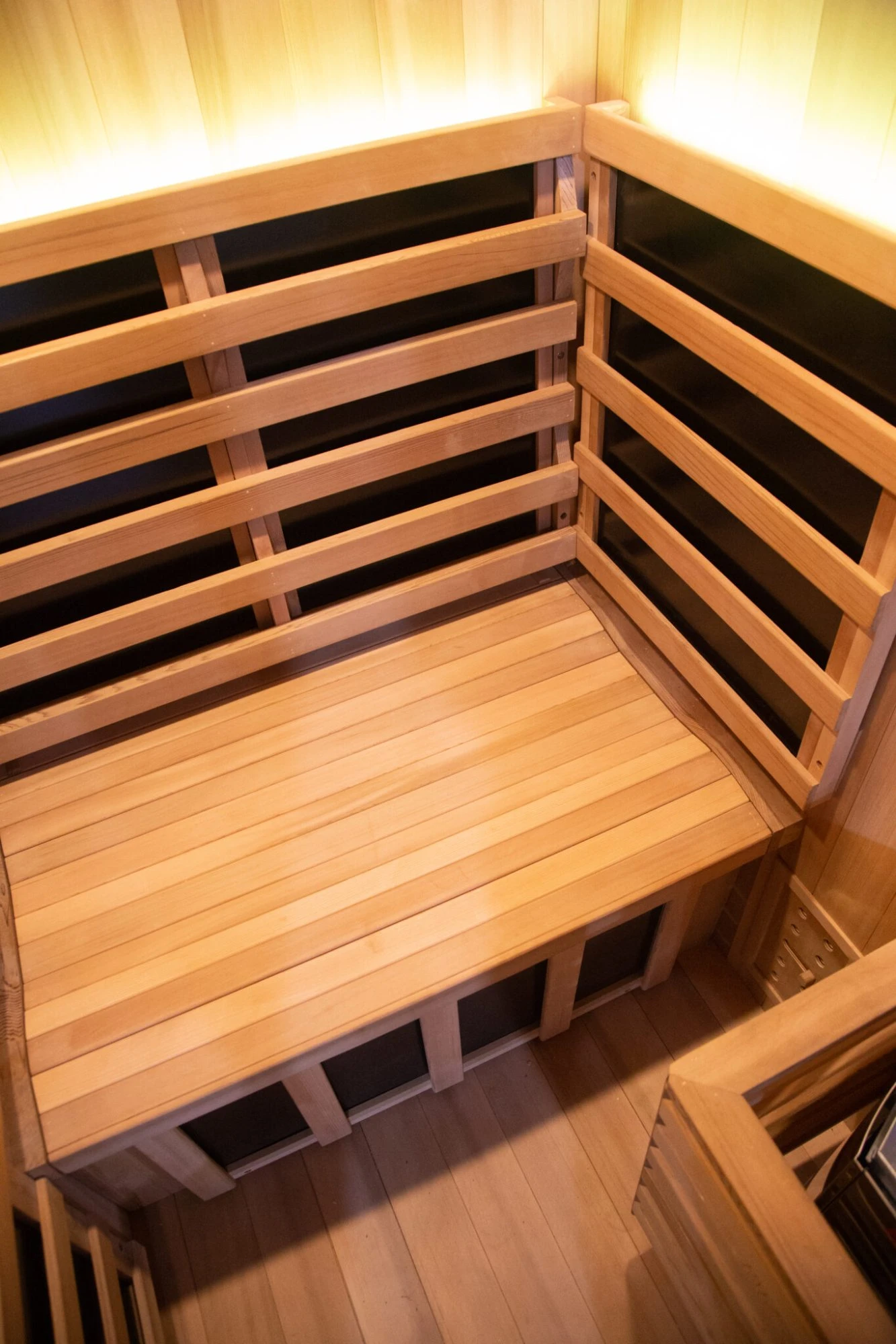 Close-up of the interior of a Solace Hybrid sauna showing the timber wall, bench seating, and infrared panels